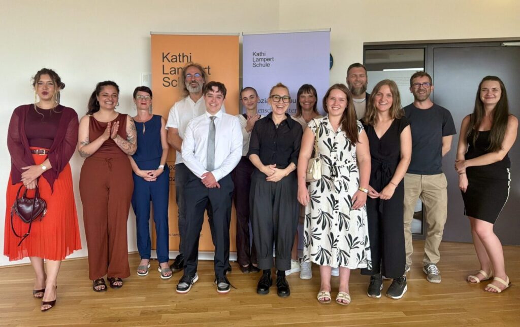 13 Studierende stehen vor den Toll-Ups der Kathi-Lampert-Schule.