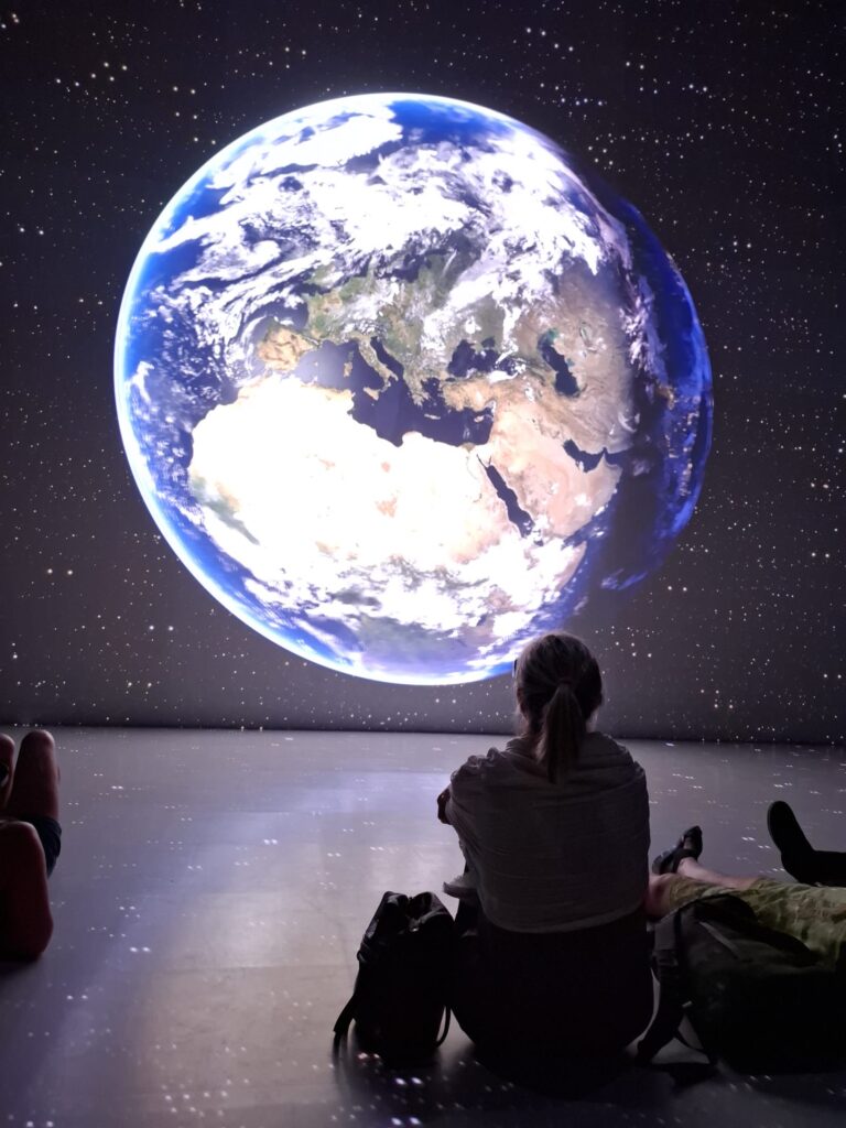 Mehrere Personen sitzen vor einer Projektion der Erdkugel.